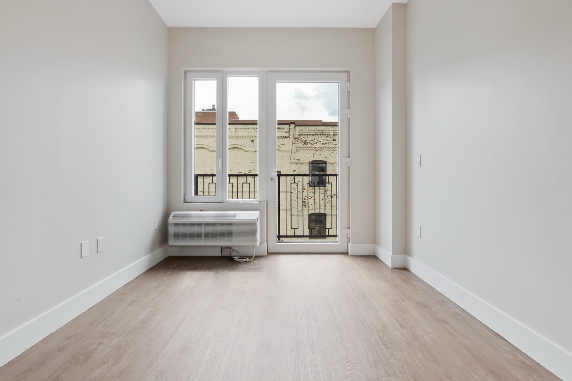 Una residencia de dos habitaciones en The Astelle con puertas de balcón de piso a techo que se abren a un paisaje de ladrillo en Mott Haven