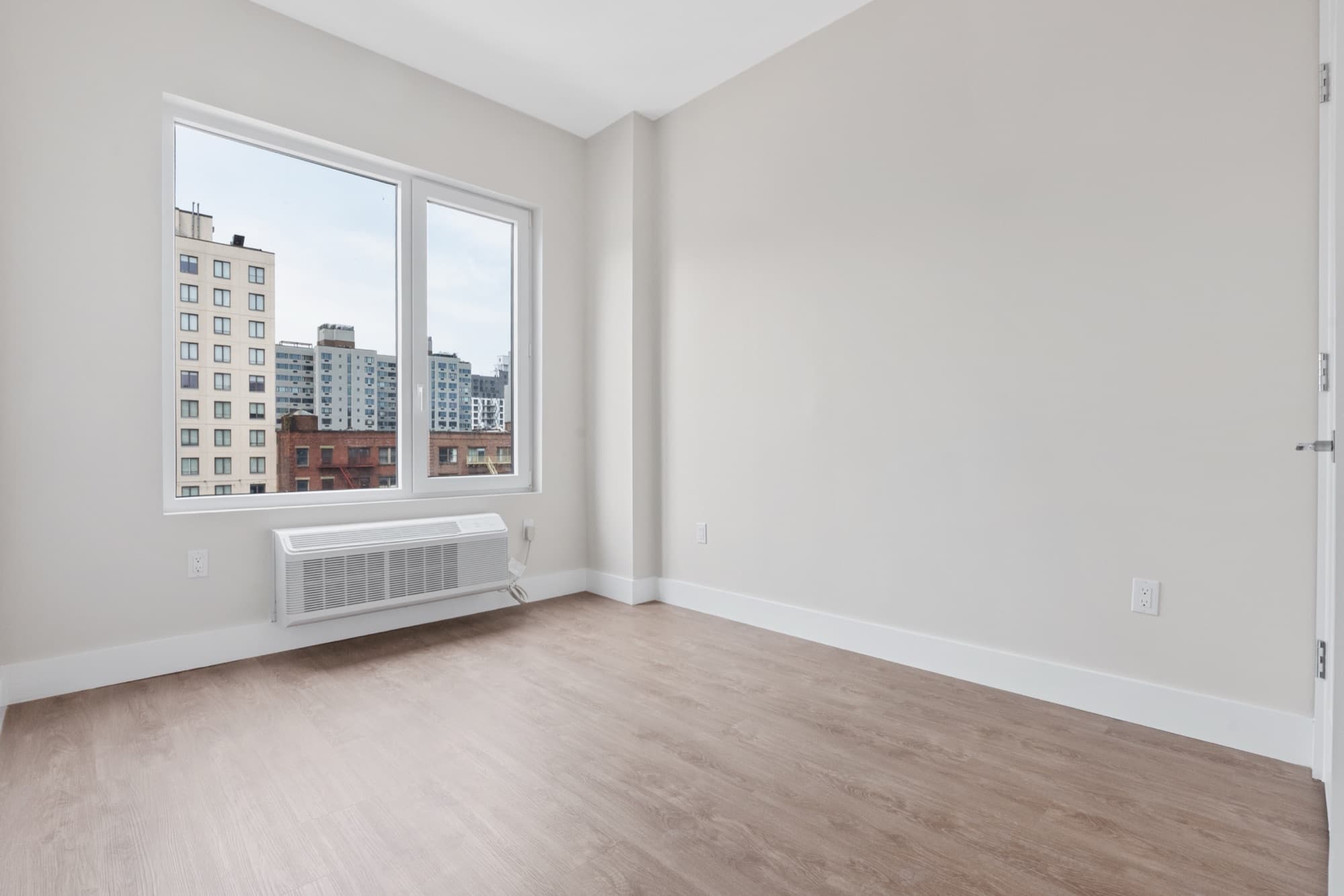 Una habitación iluminada en The Astelle con ventanales amplios con vista sobre el sur del Bronx