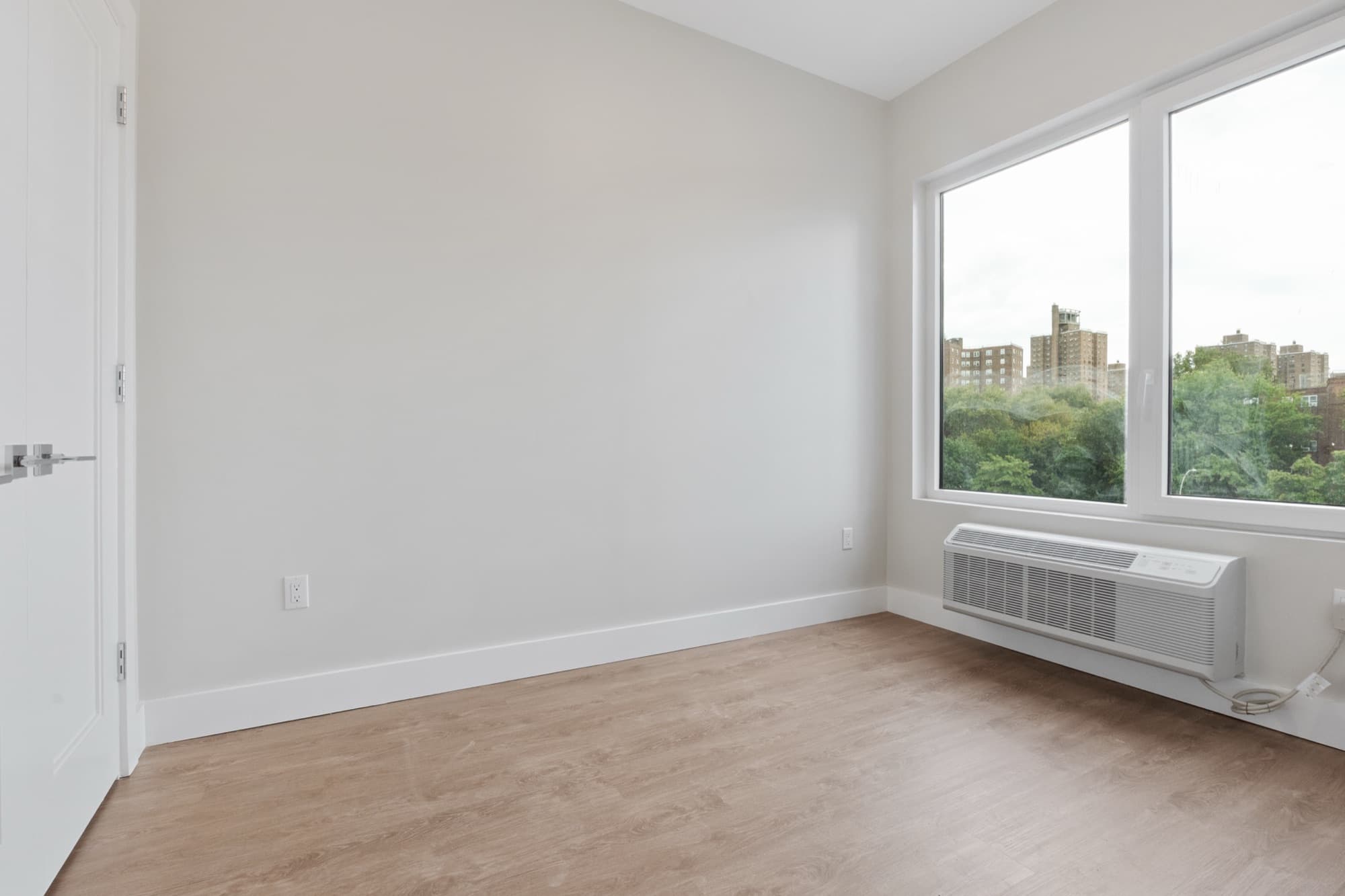 Una residencia de una habitación en The Astelle con dos ventanales amplios con vista a las copas de los árboles y al sur del Bronx