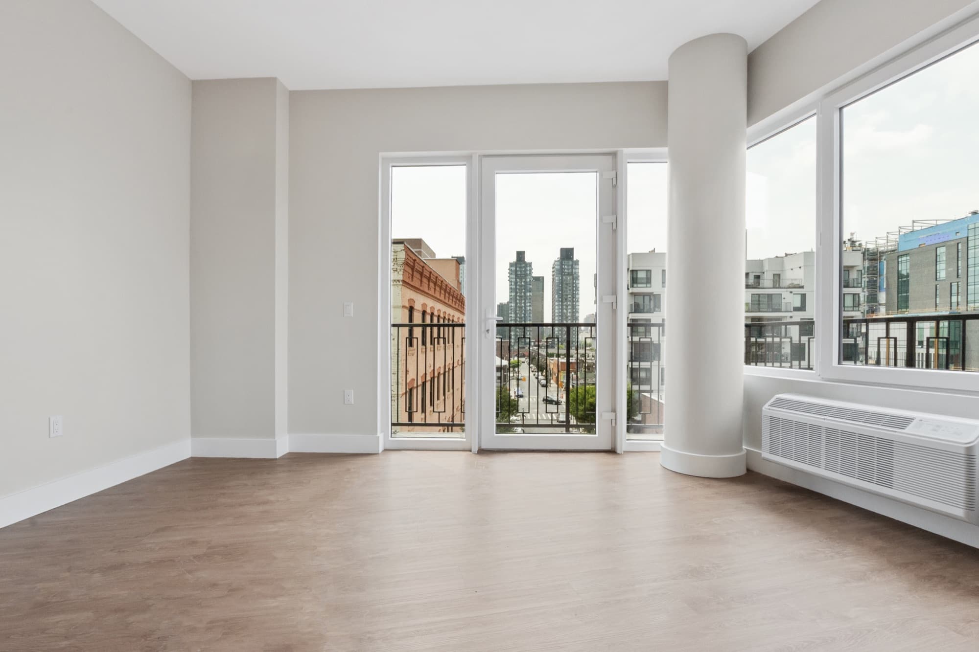 La sala de una residencia en The Astelle con luz cálida de la tarde, abierta a un balcón privado sobre Mott Haven.